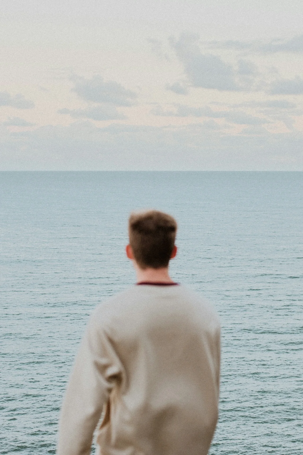 Een man kijkt vanaf de kust uit over de zee